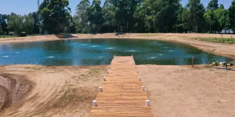 Laguna recién construida con una pasarela de madera sobre la costa de arena